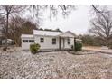 Quaint white home with covered carport and landscaped yard lightly dusted with snow on an overcast day at 5028 Wilgrove Mint Hill Rd, Mint Hill, NC 28227