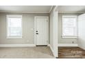 Bright living room with carpeted floors, large windows, and white trim, leading to wood-look flooring at 5028 Wilgrove Mint Hill Rd, Mint Hill, NC 28227