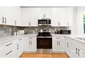 Bright kitchen with white cabinets, stainless steel appliances, and neutral backsplash at 5404 Maplewood Ln, Charlotte, NC 28227