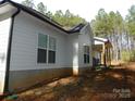 Side view of a house with white siding and black gutters surrounded by trees in a wooded lot at 128 Summerlake Dr, New London, NC 28127