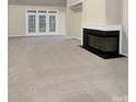Spacious living room features neutral carpeting, a modern fireplace, and french doors leading to outdoor space at 6310 Lily Pad Ct, Charlotte, NC 28262