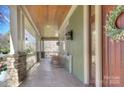 Spacious covered porch with rocking chairs, stone pillars, and a stained wood entry door at 324 Wendover Hill Ct, Charlotte, NC 28211