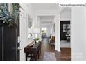 Inviting entryway with dark wood floors, white walls, decorative mirror, and a view into the dining and living areas at 447 Zender Ln, Monroe, NC 28112