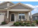 Inviting covered porch with comfortable seating, stone pillars, and a welcoming entryway at 7127 Chrysanthemum Rd, Lancaster, SC 29720