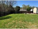 Large fenced backyard with lush green grass and stone firepit area at 1638 Marmot Pl, Concord, NC 28025