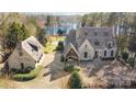 Aerial view of the stone clad home with an oversized driveway and detached garage near a lake at 20711 Bethel Church Rd, Cornelius, NC 28031