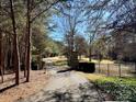 Gated driveway leading to a private estate, surrounded by mature trees and lush greenery at 20711 Bethel Church Rd, Cornelius, NC 28031