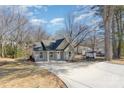 View of cozy home with expansive driveway surrounded by bare winter trees and grass in need of TLC at 290 Houston Ne St, Concord, NC 28025