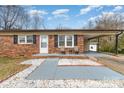 Charming brick home with a covered porch, lush landscaping, and a welcoming front entrance at 303 S Eastway Dr, Troutman, NC 28166