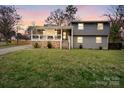 Charming two-story home at sunset featuring stone accents, a covered porch with ceiling fans, and a spacious front lawn at 3501 Winterfield Pl, Charlotte, NC 28205