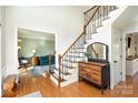 Inviting foyer with hardwood floors, a staircase with wood and iron railing, and a view into the living room at 7732 Wingmont Dr, Charlotte, NC 28269