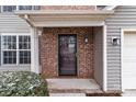 A close up of a front door, with brick surround, gray siding, and a cozy porch at 9014 Arbor Creek Dr, Charlotte, NC 28269