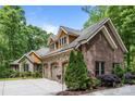 Beautiful home featuring a stone and brick exterior, three-car garage, manicured landscaping, and charming dormer windows at 11280 Mcfalls Dr, Fort Mill, SC 29707
