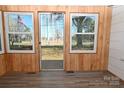 Sunroom with wood paneling, new vinyl flooring, and large windows showcasing the surrounding landscape at 1433 Buffalo Shoals Rd, Catawba, NC 28609