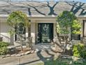 Inviting front porch with stone supports, a black front door, lush greenery, and decorative accents at 4631 Dawnridge Dr, Charlotte, NC 28226