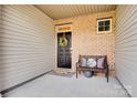 Inviting front porch boasts a black door, brick columns, and a cozy bench at 5212 Spanish Ivy Ln, Indian Land, SC 29707