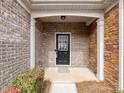 A covered entrance with a black front door and brick and stone accents at 6449 Silver Star Ln, Charlotte, NC 28210