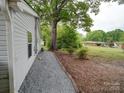 Landscaped side yard view with trees and a glimpse of a neighboring house in a peaceful setting at 709 High St, Albemarle, NC 28001