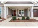Inviting front porch featuring white columns, a red front door, and meticulously maintained landscaping at 4000 Spring Cove Way, Belmont, NC 28012