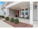 Inviting front porch featuring white columns, a red front door, and meticulously maintained landscaping at 4000 Spring Cove Way, Belmont, NC 28012