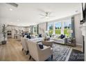 Bright, open living room with large windows, hardwood floors, modern furniture, and a view to the kitchen at 4004 Caymen Bay Ct, Tega Cay, SC 29708