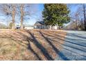 Quaint single-story home with mature trees and a gravel driveway under a clear blue sky at 28419 Nc Hwy 73 Hwy, Albemarle, NC 28001