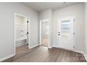Bright hallway featuring modern wood-look flooring, leading to a bathroom with a tub and an open doorway to another room at 3606 Clover Valley Dr, Gastonia, NC 28052