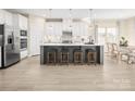 Spacious kitchen with stainless steel appliances, a gray island with stool seating, and light wood flooring at 497 Kenyon Dr, Denver, NC 28037