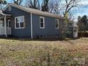 Exterior view of a blue home with white-trimmed windows and a well-maintained yard with some exposed foundation at 827 W Horah St, Salisbury, NC 28144