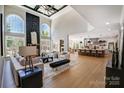 Open-concept living room with soaring ceilings, fireplace, large windows, and seamless flow to the kitchen at 8707 Fairview Rd, Charlotte, NC 28226