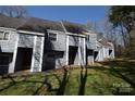 Townhouse featuring gray siding, front entryway with steps, and green grassy lawn at 9129 Troon Ln # C, Charlotte, NC 28214