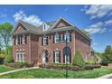 Traditional two-story red brick home with black shutters, well-manicured landscaping, and street sign at 100 Cliveden Ct, Belmont, NC 28012