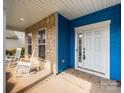 Inviting front porch featuring stone accents, rocking chairs, and a bright white front door at 10826 Saltmarsh Ln, Charlotte, NC 28278