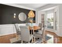 Stylish dining room featuring wainscoting, a modern light fixture, and a bay window at 11001 Valley Spring Dr, Charlotte, NC 28277