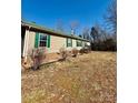 Side view of a beige home featuring a well-maintained lawn, green shutters, and a metal roof at 191 Ashford Dr, Olin, NC 28660