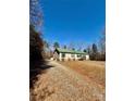 Cozy single-story home with a gravel driveway, a metal roof, and surrounded by trees at 191 Ashford Dr, Olin, NC 28660