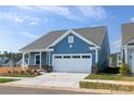 Exterior of a charming blue home featuring an attached garage and manicured landscaping at 40189 Crooked Stick Dr # 1205, Lancaster, SC 29720