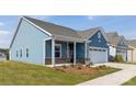 Charming blue home featuring a covered porch, attached garage, and well-maintained landscaping at 40189 Crooked Stick Dr # 1205, Lancaster, SC 29720