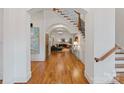 Open-concept foyer with hardwood floors, staircase with iron balusters, and arched doorways at 4336 Tottenham Rd, Charlotte, NC 28226