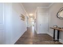 Long hallway with wood floors and white trim and doors featuring a table with clock and decorative pieces at 5024 Grace View Dr, Pineville, NC 28134