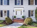 Close up of home's entrance with white door, brick steps, and manicured bushes at 555 Manning Dr # 7, Charlotte, NC 28209