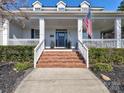 Inviting front entrance with brick steps, white railing, covered porch, and American flag at 8817 Kerns Meadow Ln, Huntersville, NC 28078