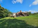Expansive backyard featuring a covered patio area, mature trees, and lush green grass at 130 Scism Rd, Kings Mountain, NC 28086