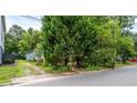 Exterior view of home showing gravel driveway and mature landscaping with shade trees at 1716 Umstead St, Charlotte, NC 28205