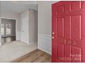 Bright foyer featuring a red front door, carpeted floors, and white wainscoting at 3203 Arklow Rd, Charlotte, NC 28269