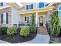 Welcoming front porch adorned with a charming wreath, flowering bushes, and inviting chairs at 5019 Mill Creek Rd, Clover, SC 29710