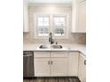 Close-up of kitchen sink with stainless steel appliances, white cabinets, and subway tile backsplash at 2918 Medlin Rd, Monroe, NC 28112