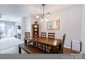 Modern dining room with stylish lighting and wood floors, open to the living area at 14941 Santa Lucia Dr, Charlotte, NC 28277