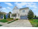 Charming two-story home with gray siding, an orange front door, a covered porch, and a two-car garage at 15307 Country Lake Dr, Pineville, NC 28134