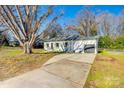 Single-story home with an attached garage and a large concrete driveway with green lawn at 1865 Woodland Dr, Charlotte, NC 28205